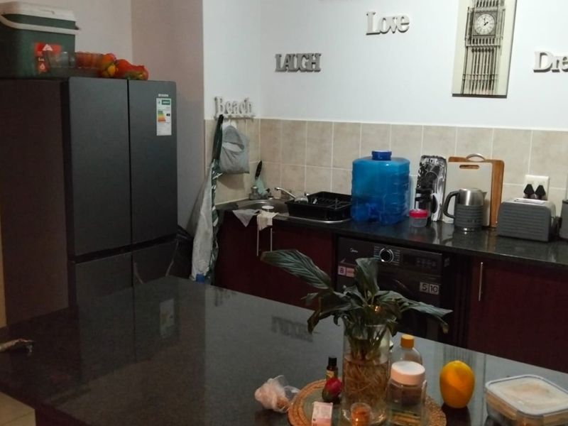 A functional kitchen featuring dark cabinetry, granite countertops, a tiled backsplash, and an integrated washing machine, providing a practical workspace.