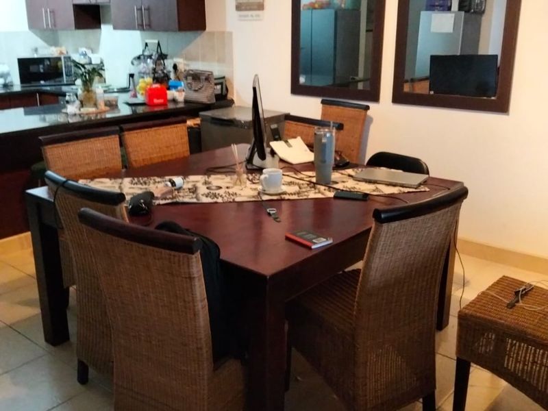Open plan dining and kitchen area featuring tiled flooring, dark wood cabinetry, and wall-mounted mirrors, providing a functional living space.