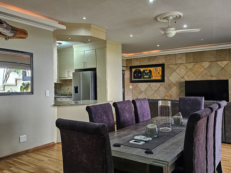 Spacious open-plan living and dining area featuring a stone tile accent wall, recessed lighting, and a functional kitchen with granite countertops.