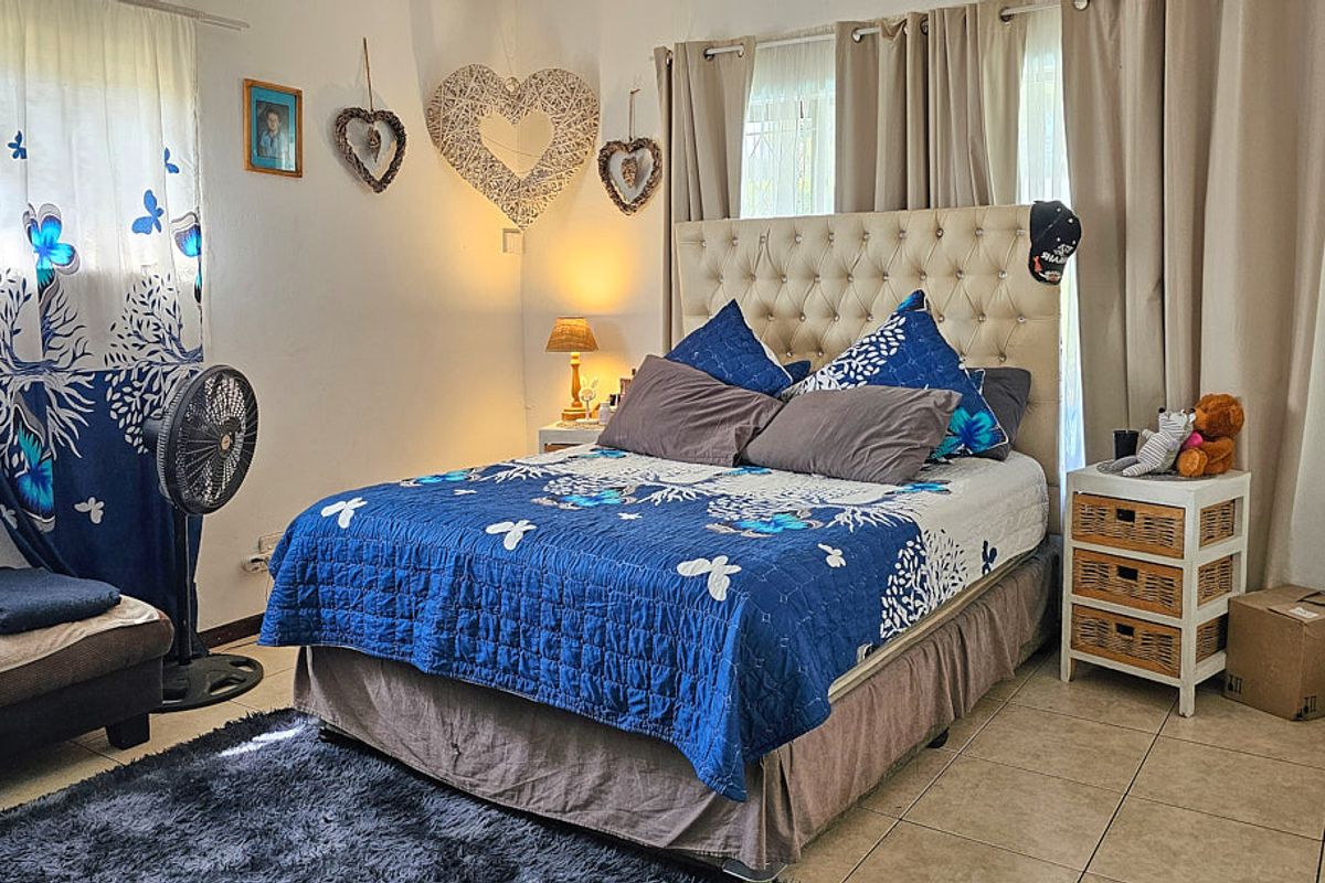 A bedroom featuring tiled flooring and neutral wall finishes, providing a functional space with natural light through window treatments.