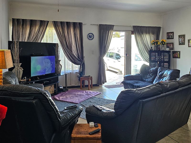A functional living room featuring tiled flooring and a sliding glass door providing access to the exterior.