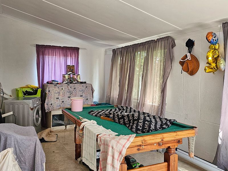 A multi-purpose living space featuring tiled flooring and panelled ceilings, currently utilized as a recreational area.