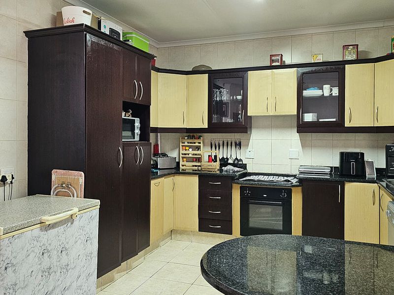 A functional kitchen featuring two-tone cabinetry, granite countertops, a built-in oven, and tiled finishes throughout.