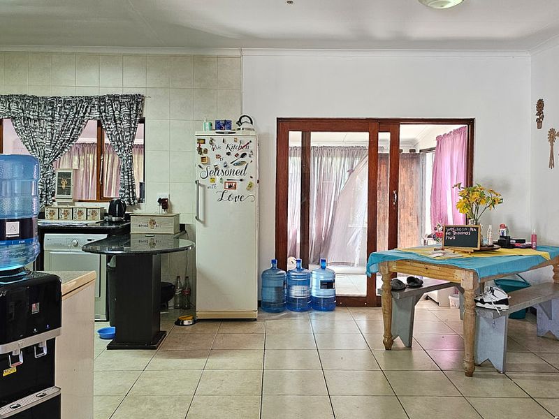 Open plan kitchen and dining area featuring tiled flooring, granite countertops, and sliding glass doors leading to an outdoor space.