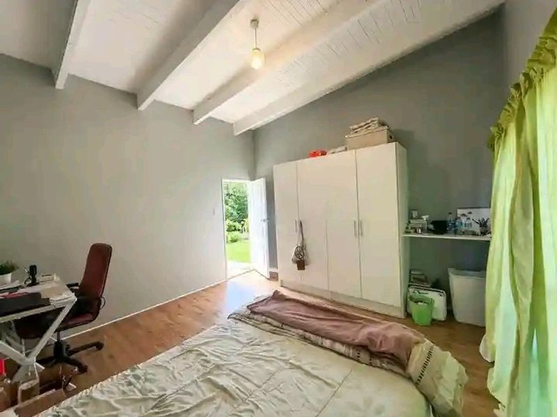 Bedroom featuring exposed beam ceilings, laminate flooring, and direct access to the garden through an external door.