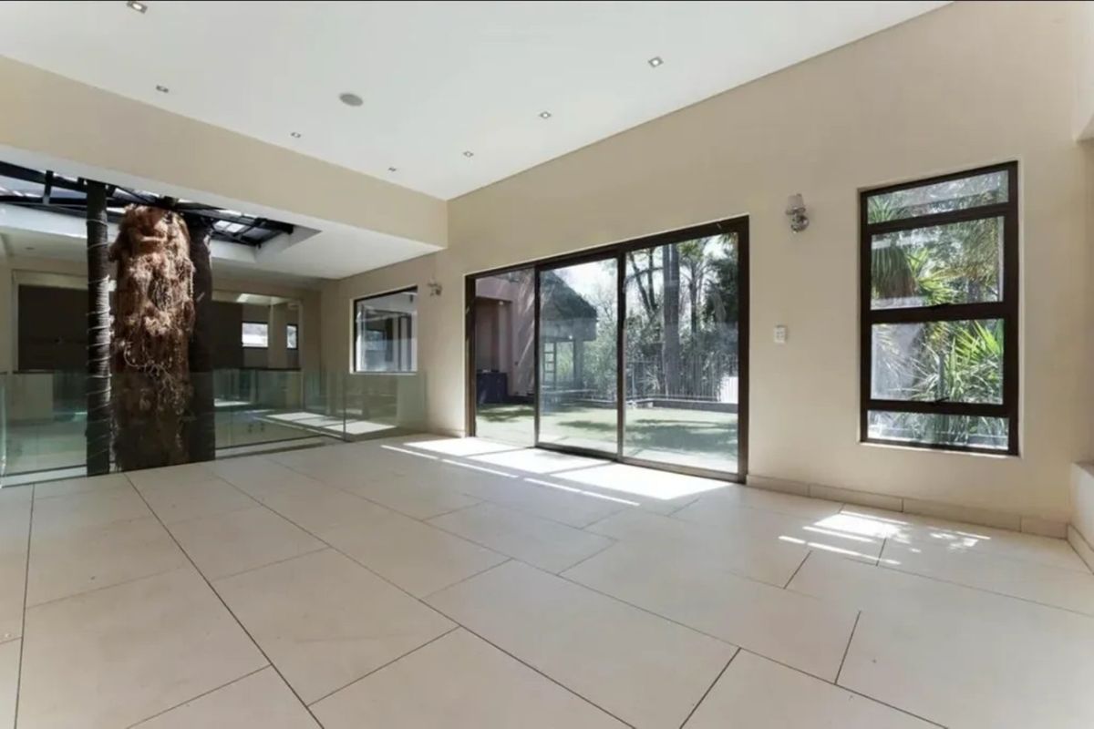 Spacious, light-filled living area featuring large format floor tiles, recessed lighting, and expansive sliding glass doors opening to the garden.