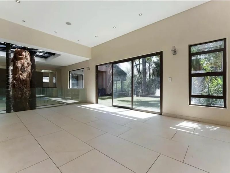 Spacious, light-filled living area featuring large format floor tiles, recessed lighting, and expansive sliding glass doors opening to the garden.