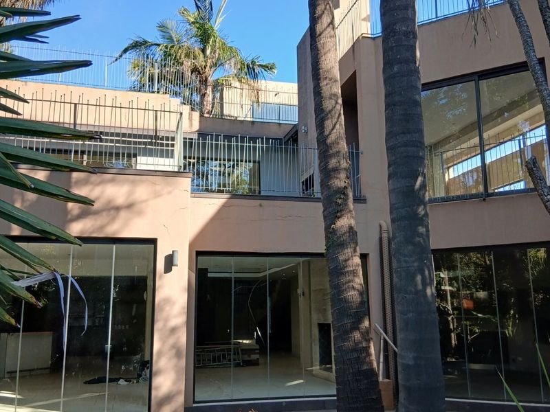 Rear view of a multi-level home featuring a swimming pool, paved patio area, and large sliding glass doors leading into the living spaces.