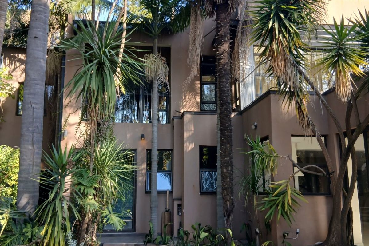 Rear view of a multi-level house featuring a swimming pool, tiled patio area, and established garden landscaping.