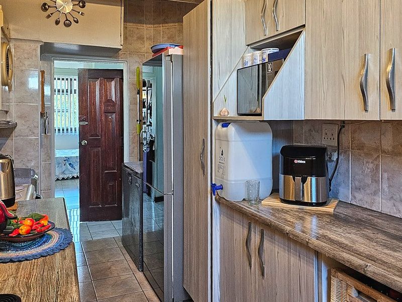 A functional kitchen featuring laminate cabinetry, tiled walls, and tiled flooring, offering a practical layout with ample storage space.