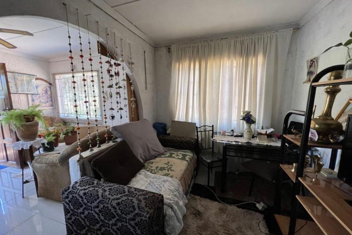 A living room area featuring an arched entryway and tiled flooring, requiring cosmetic updates to improve the overall aesthetic and condition of the space.