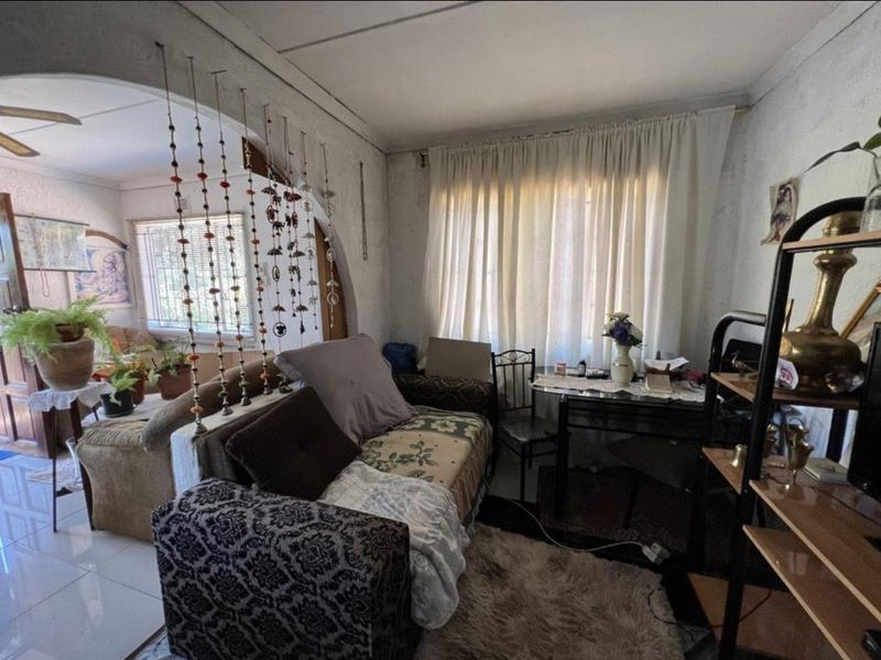 A living room area featuring an arched entryway and tiled flooring, requiring cosmetic updates to improve the overall aesthetic and condition of the space.