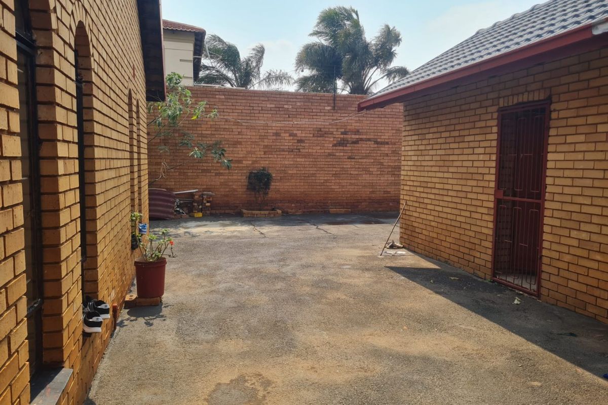 A private rear courtyard featuring face brick walls, paved flooring, and a secure entrance, offering potential for a landscaped outdoor entertainment area.