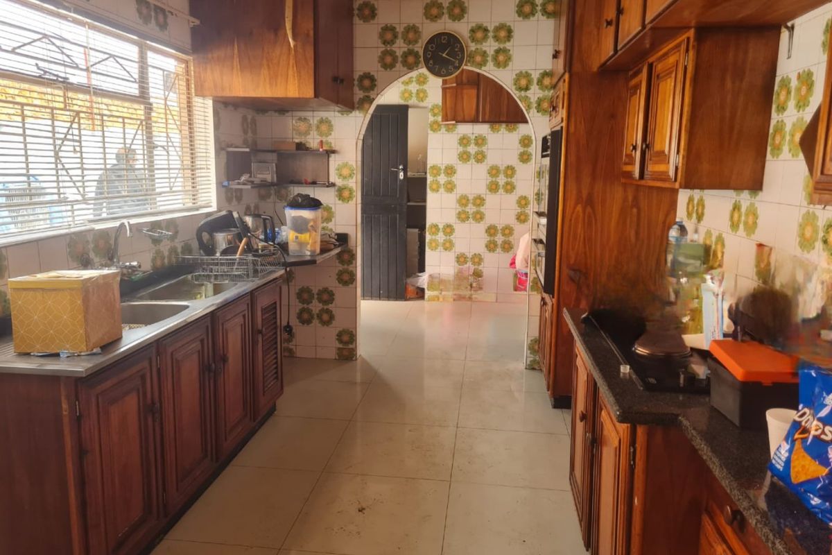 A dated kitchen featuring traditional wooden cabinetry, tiled walls, and a double basin sink, offering significant potential for a modern renovation.
