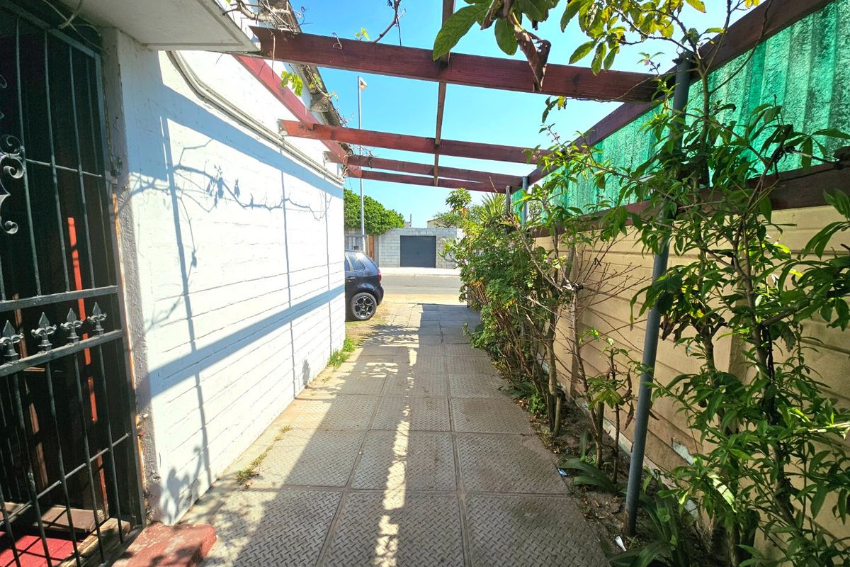 A side walkway featuring a paved path, timber pergola structure, and boundary wall, providing access along the side of the property.