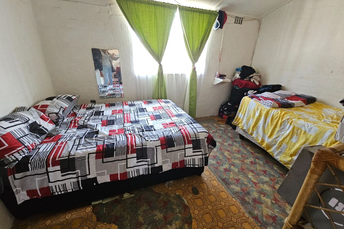 A bedroom featuring a window with curtain rod, requiring cosmetic updates to the flooring and wall finishes to improve the overall condition.