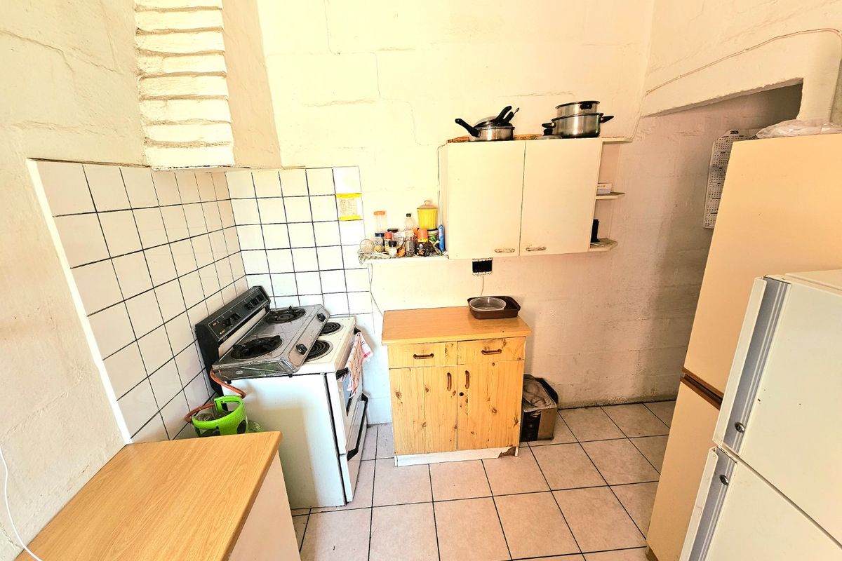 A compact kitchen featuring a gas stove, tiled splashback, and basic cabinetry, offering potential for modernization and improved storage layout.