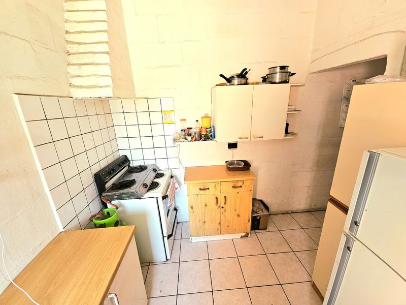 A compact kitchen featuring a gas stove, tiled splashback, and basic cabinetry, offering potential for modernization and improved storage layout.