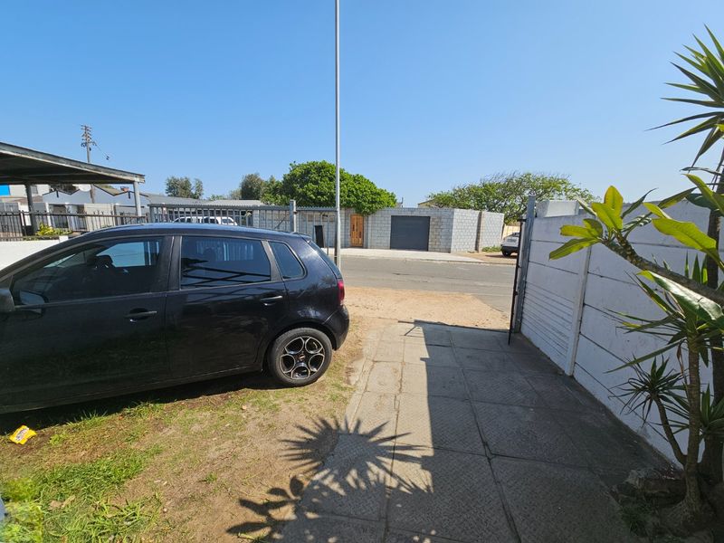 A view of the property entrance featuring a paved driveway, concrete boundary wall, and metal gate access from the street.