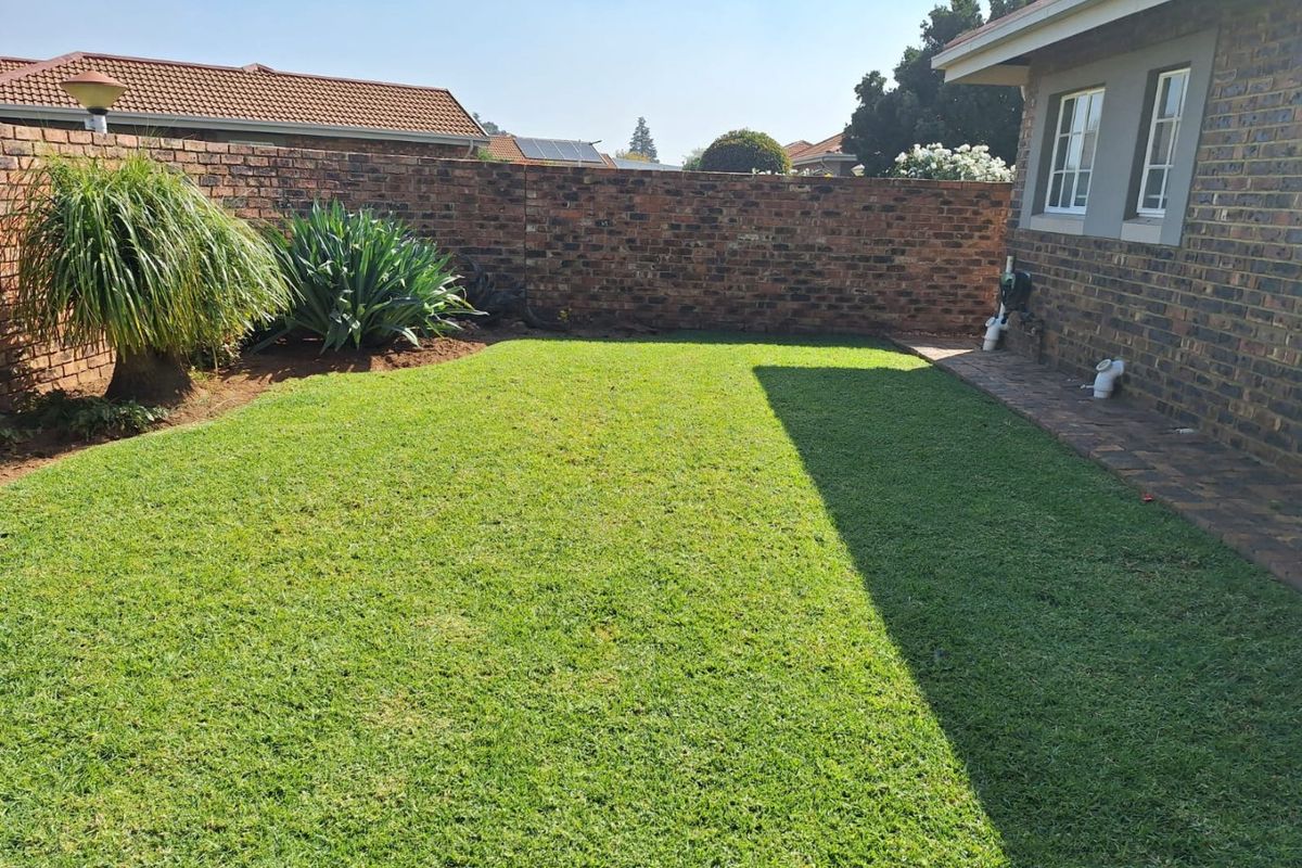 A private rear garden featuring a well-maintained lawn, paved walkway, and secure brick boundary wall, providing a clean and functional outdoor space.