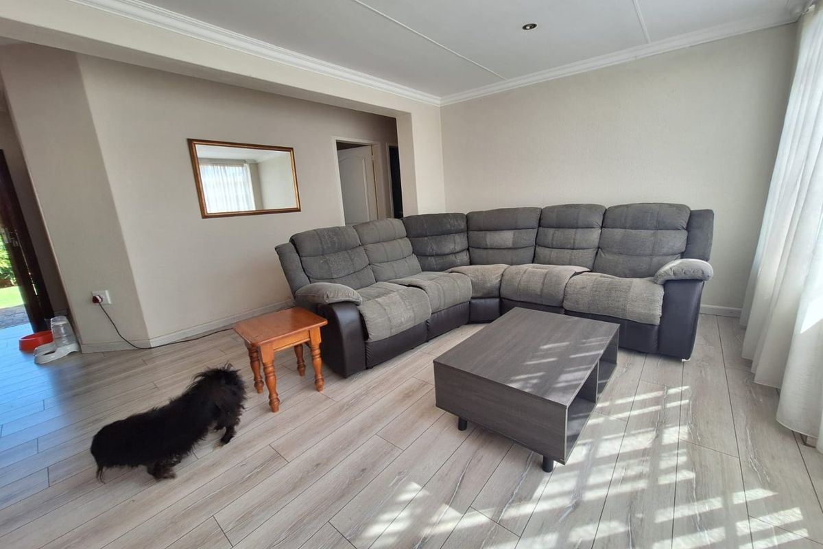 A bright living room featuring modern light-toned laminate flooring, neutral wall finishes, and recessed ceiling lighting, providing a clean and functional living space.
