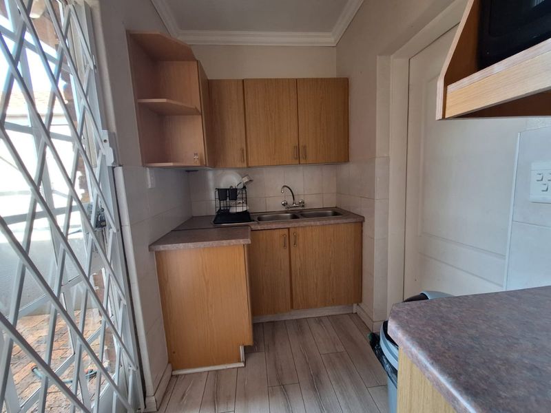 Compact scullery area featuring laminate cabinetry, double basin sink, and tiled splashback, providing functional prep and wash-up space.