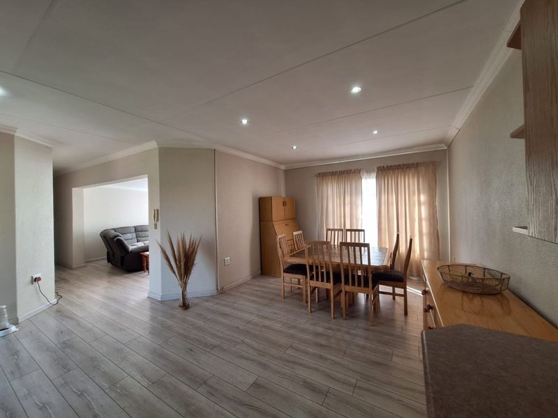 Open-plan living and dining area featuring modern laminate flooring, recessed downlighting, and neutral wall finishes, creating a bright and functional living space.