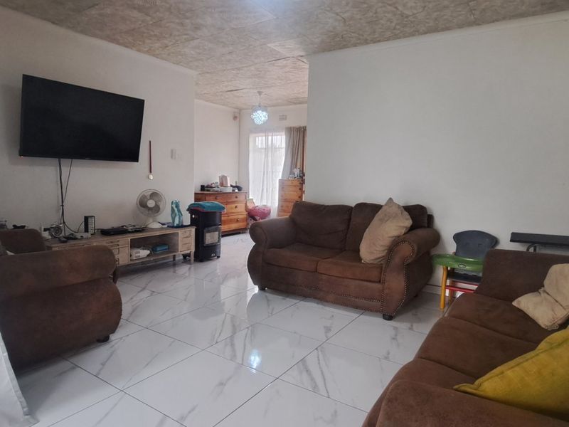 Spacious living room featuring polished marble-look floor tiles and a textured ceiling, offering a bright and open layout.