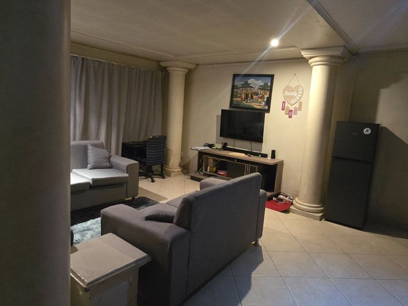 A spacious living area featuring tiled flooring and decorative structural columns, providing a versatile layout for comfortable seating and entertainment.