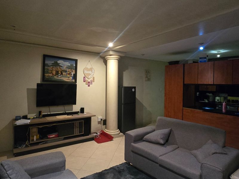 Open-plan living area featuring tiled floors, decorative columns, and an integrated kitchen with wooden cabinetry.