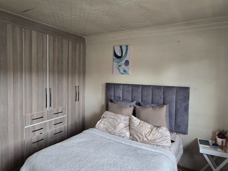 A bedroom featuring extensive built-in wooden cupboards and a neutral color palette, requiring ceiling repairs to improve the overall condition.