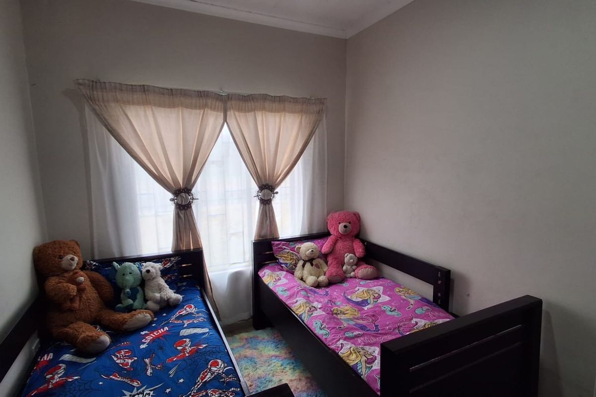 A functional bedroom featuring a window with installed curtain rods, providing natural light and space for sleeping arrangements.