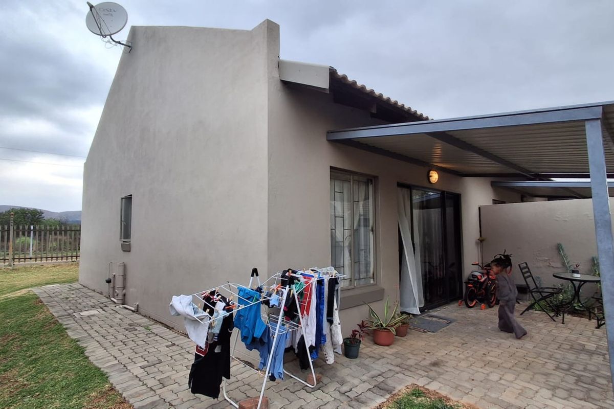 Rear view of the townhouse featuring a paved patio area, covered outdoor space, and sliding door access to the interior.