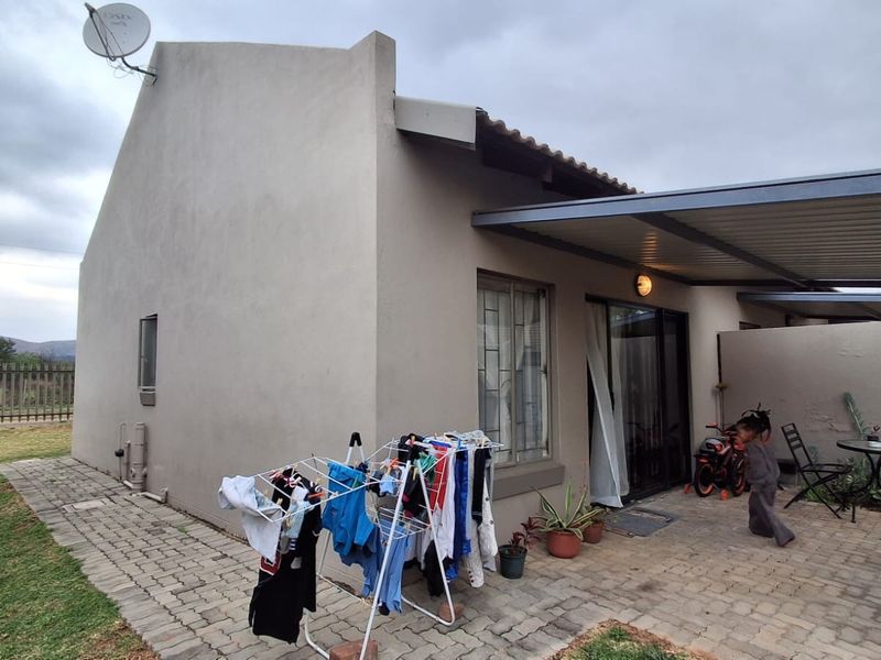 Rear view of the townhouse featuring a paved patio area, covered outdoor space, and sliding door access to the interior.