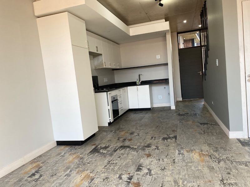 Modern kitchen featuring white cabinetry, dark stone countertops, built-in oven, and hob, set against a contemporary concrete-look tiled floor.