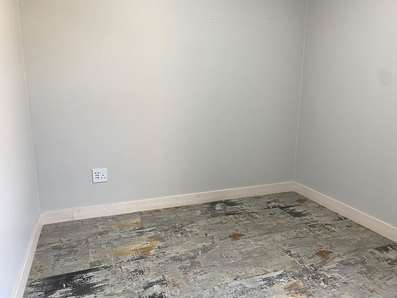 An empty bedroom featuring patterned vinyl flooring and neutral wall finishes, providing a blank canvas for potential interior design updates.