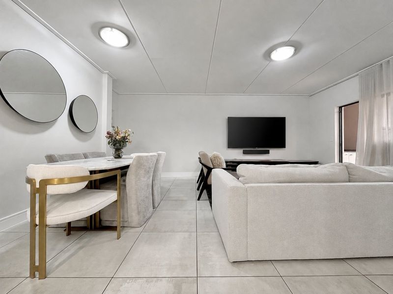 A bright and spacious open-plan living and dining area featuring neutral tiled flooring and modern recessed ceiling lighting.