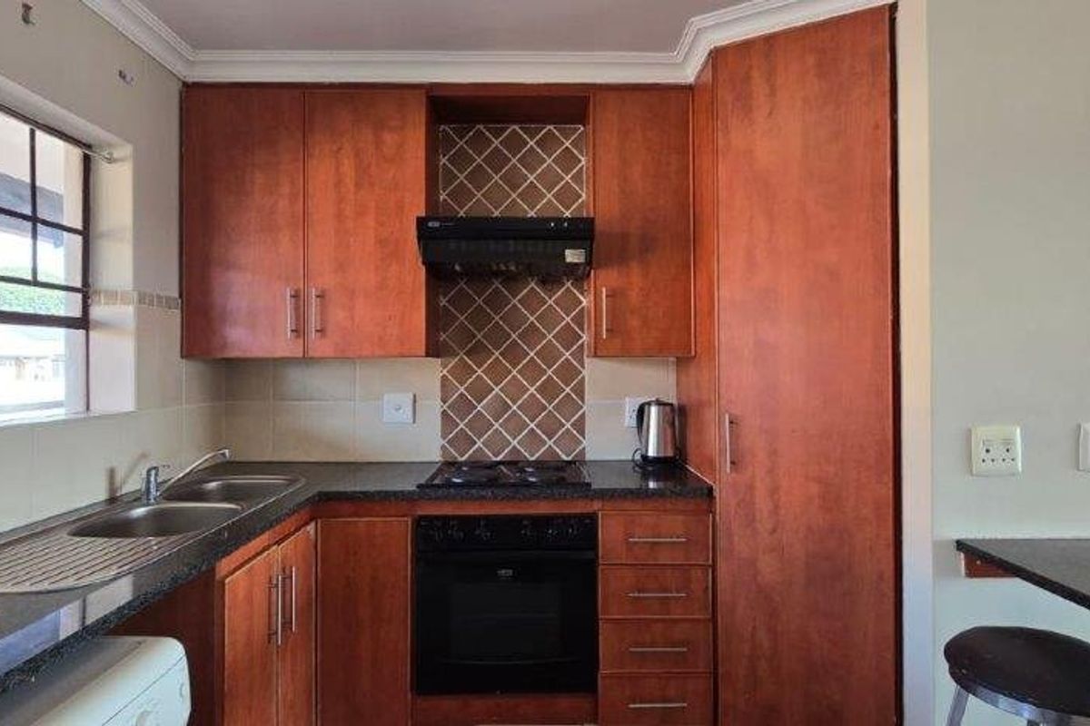 A functional kitchen featuring wood-finish cabinetry, granite countertops, a built-in oven with gas hob, and a convenient breakfast bar area.