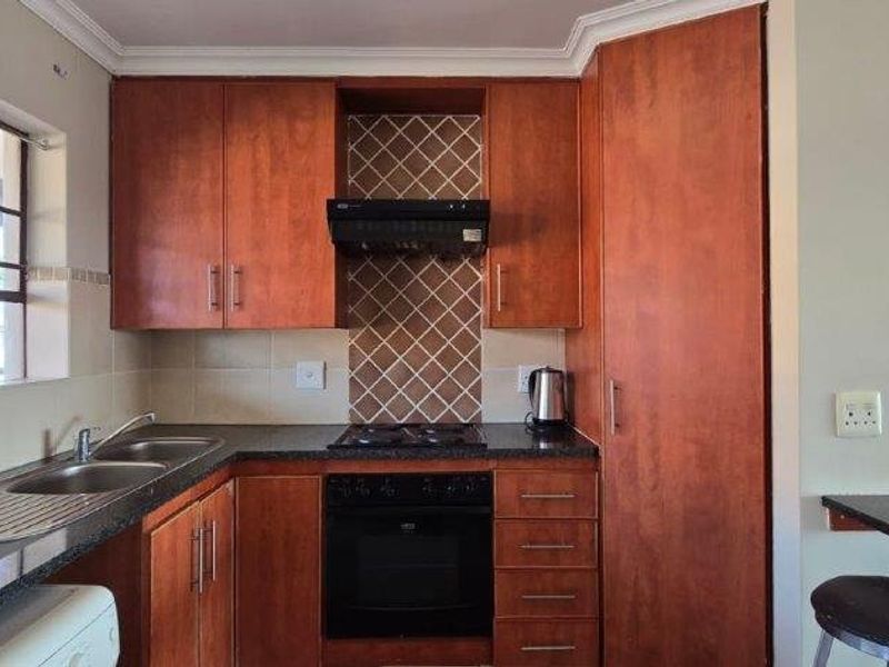 A functional kitchen featuring wood-finish cabinetry, granite countertops, a built-in oven with gas hob, and a convenient breakfast bar area.