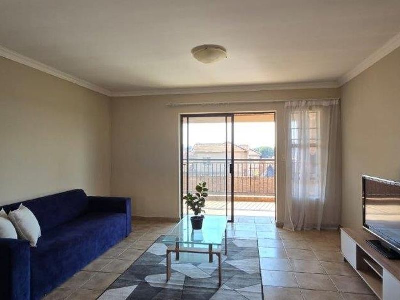A living room featuring tiled flooring and a sliding glass door that opens onto a balcony, providing natural light and access to outdoor space.