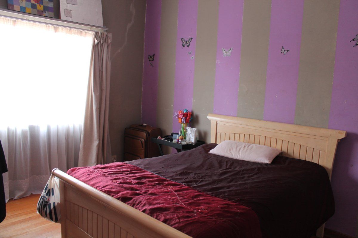 A bedroom featuring timber flooring and a window with curtain rails, currently requiring cosmetic updates to the wall finishes.