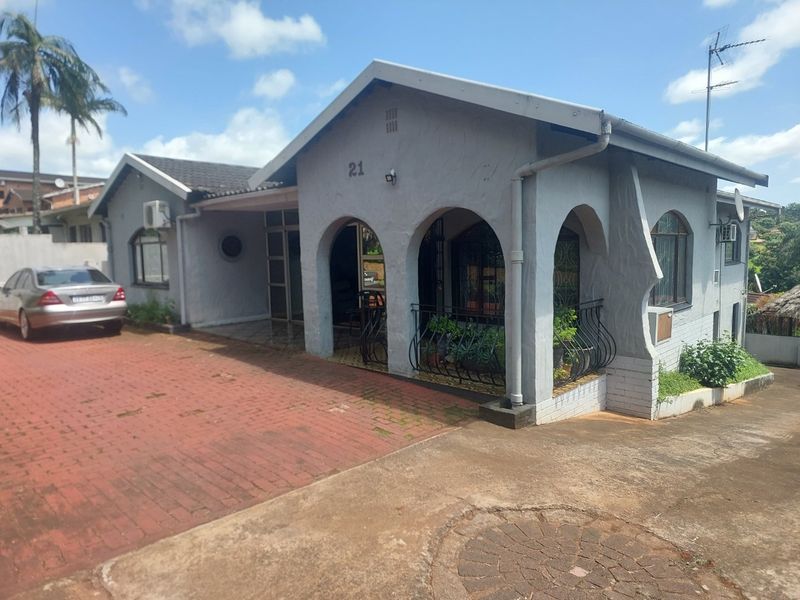 Front elevation of a single-story house featuring an arched veranda, paved driveway, and established exterior finishes.
