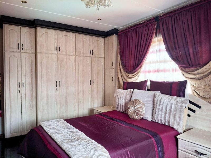A bedroom featuring extensive built-in wooden cupboards and recessed ceiling lighting, providing ample storage and a functional layout.