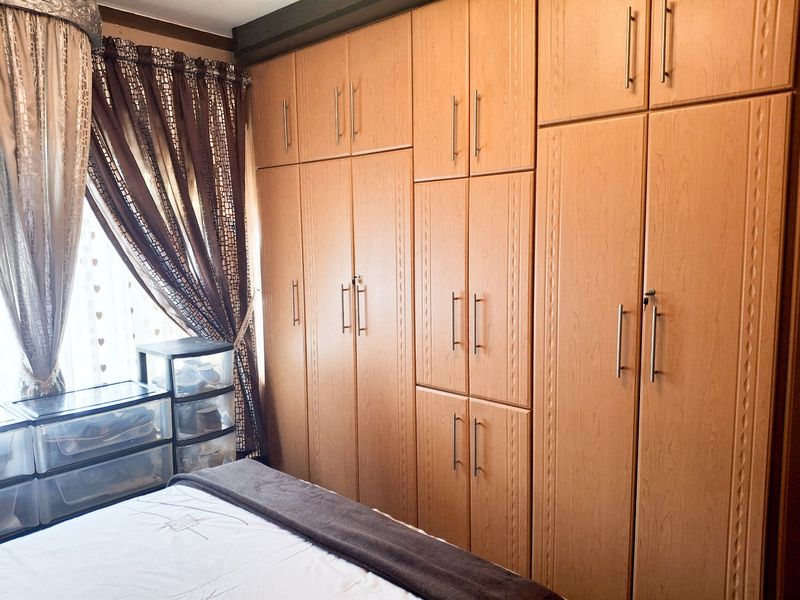 A bedroom featuring extensive floor-to-ceiling built-in wooden cupboards providing ample storage space.