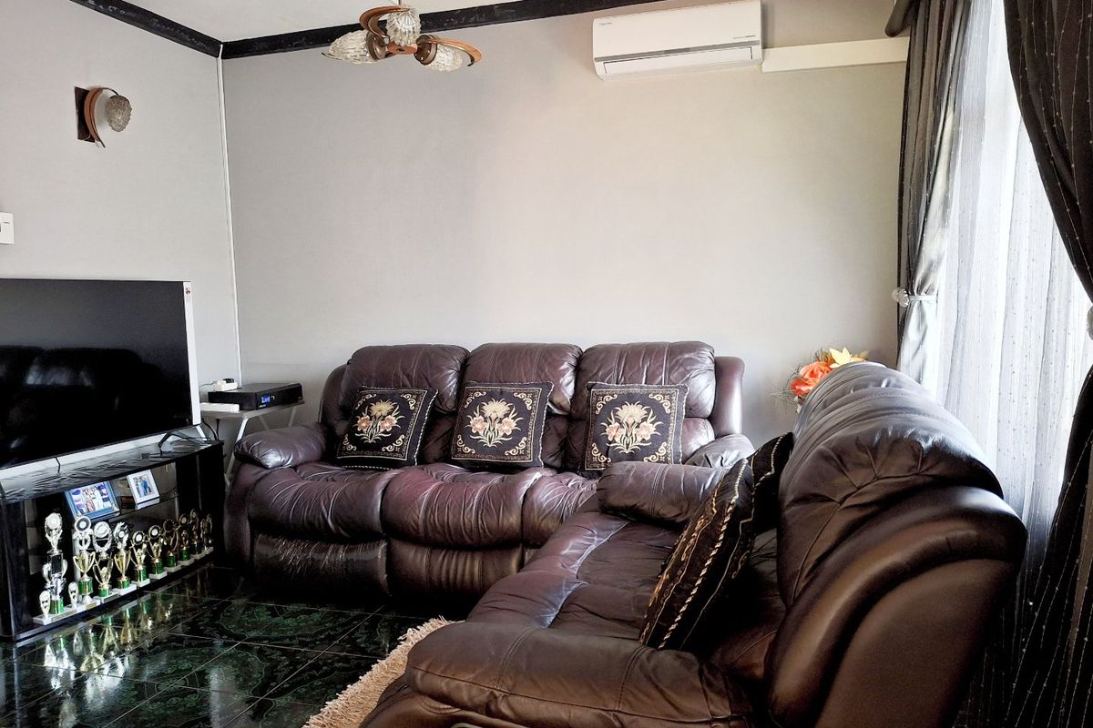 A comfortable living room featuring dark ceramic floor tiles, a wall-mounted split-system air conditioner, and decorative lighting fixtures.