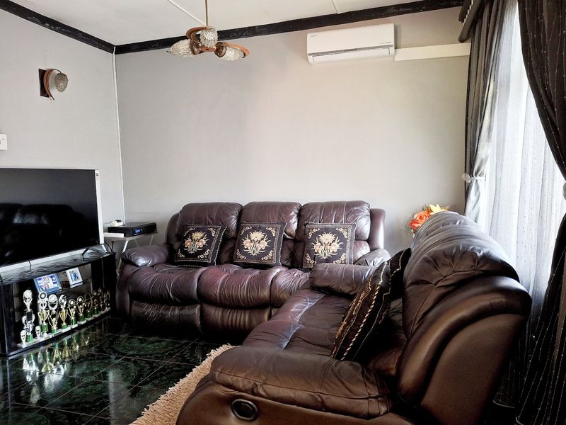 A comfortable living room featuring dark ceramic floor tiles, a wall-mounted split-system air conditioner, and decorative lighting fixtures.
