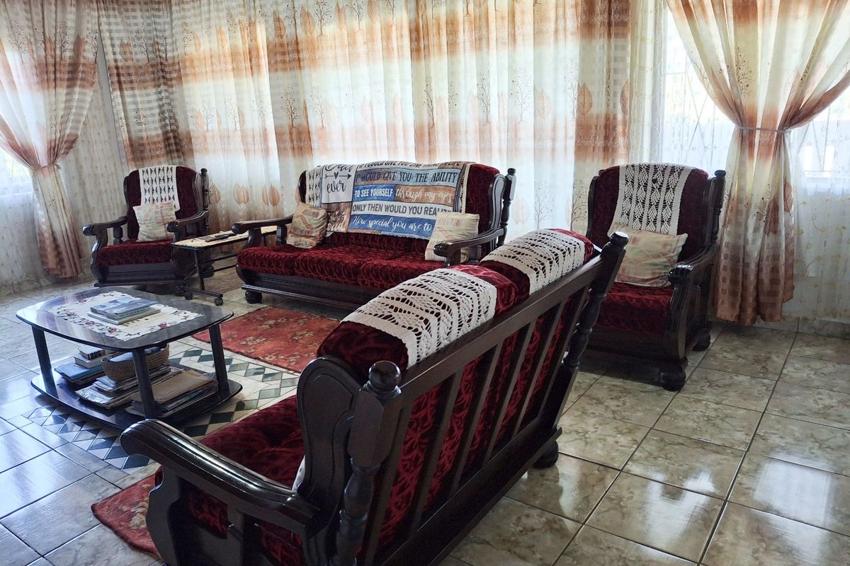 A living room featuring ceramic floor tiles and full-length window curtains.