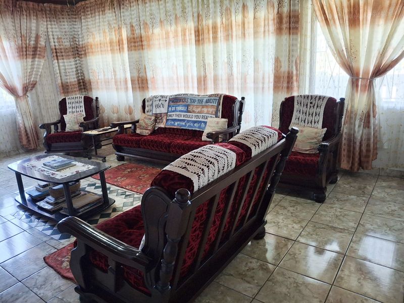 A living room featuring ceramic floor tiles and full-length window curtains.