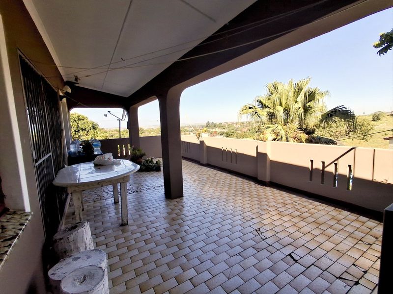 A spacious covered balcony featuring tiled flooring and a masonry balustrade, offering an open outdoor area with scenic views.