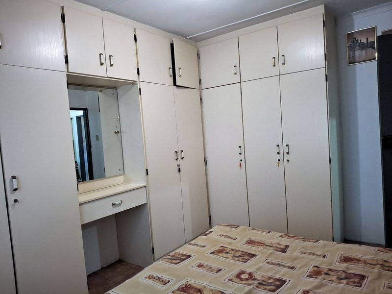 Bedroom featuring extensive built-in cabinetry with an integrated vanity and mirror, providing ample storage space.
